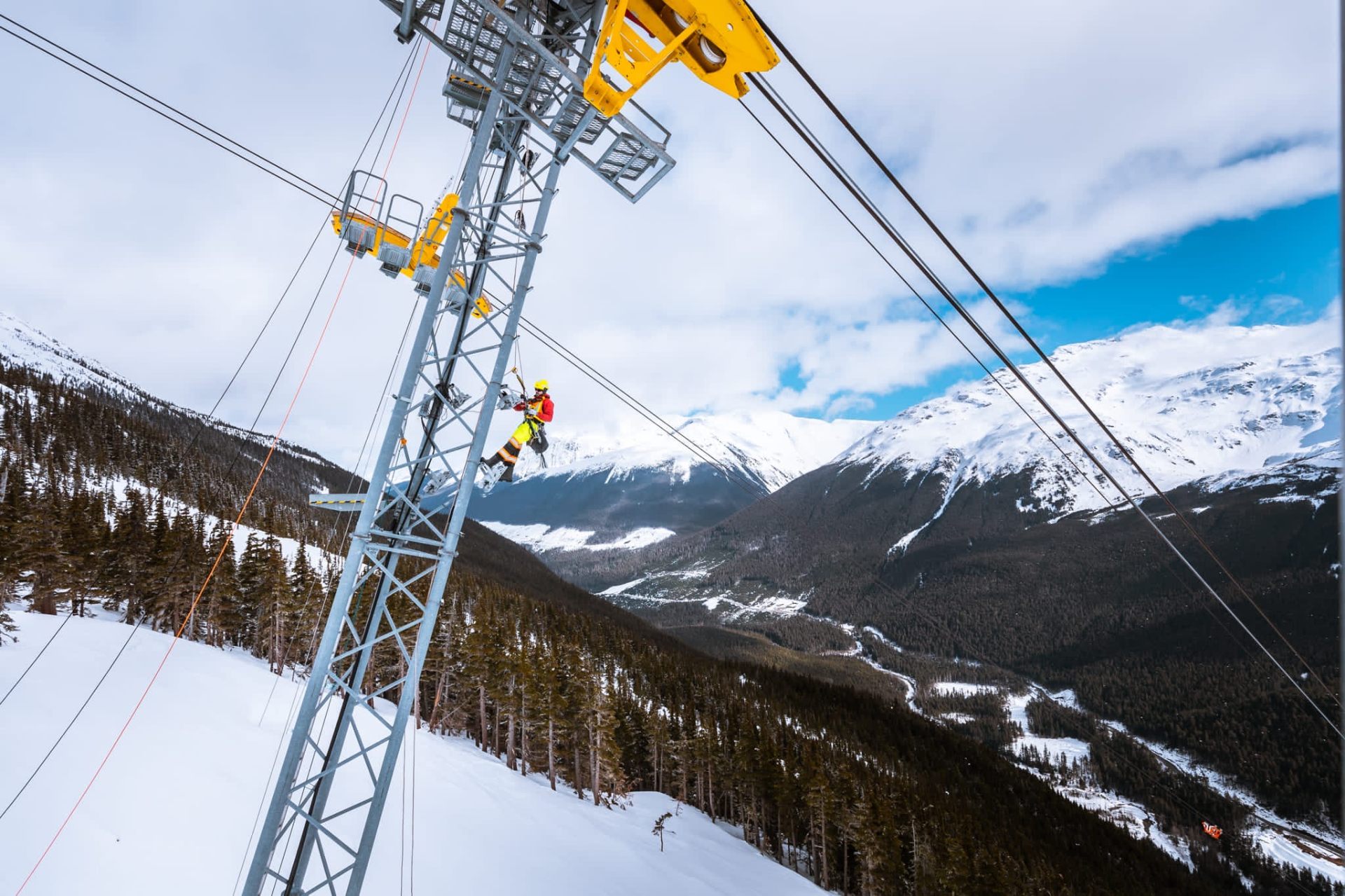 Wide mountain panorama with a steel tower and a technician at work